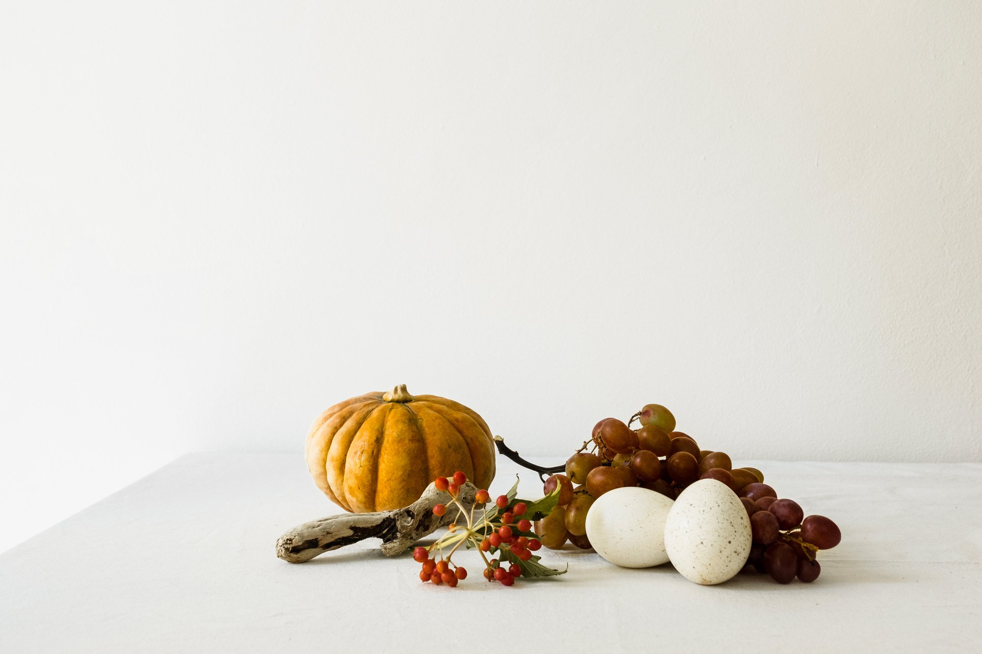 Pumpkin, Grapes, and Eggs on White Table